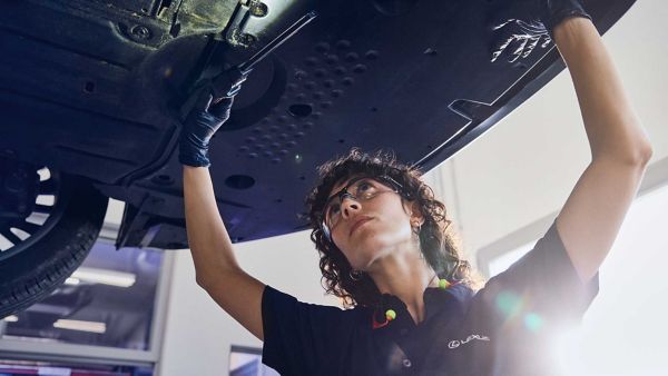 Ein Lexus-Mechaniker inspiziert den Unterboden eines Fahrzeugs