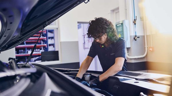 A Lexus mechanic working under the bonnet of a car