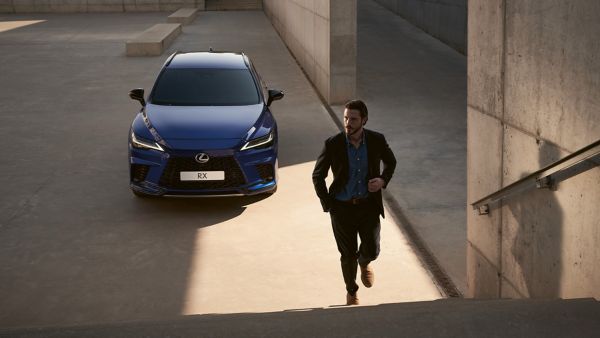 Een persoon die een trap oploopt met een Lexus RX op de achtergrond