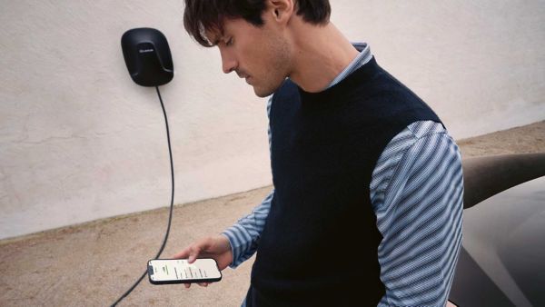 A person using a mobile phone stood in front of a Lexus Homecharge