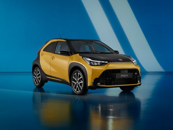 Der neue, gelbe Aygo X, steht seitlich zur Kamera vor einer blauen Leinwand.