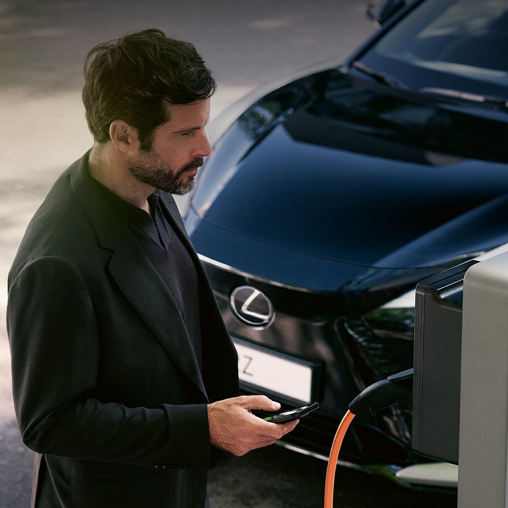 A Lexus RZ driver stood next to a charger