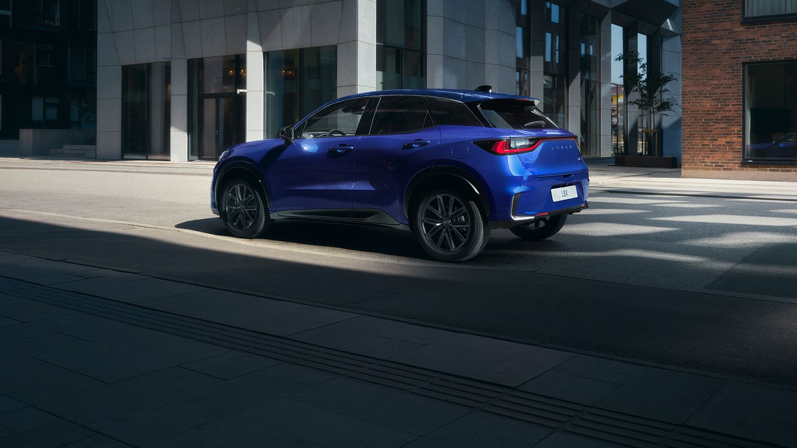Manneskja gengur aftan við kyrrstæðan Lexus LBX