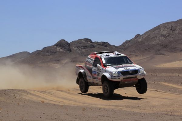 Hilux profile shot blistering through desert kicking up sand