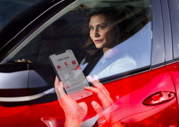 Hand bedient Smartphone mit Pannenapp - Person sitzt in einem roten Auto