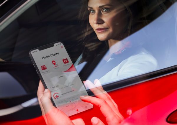 Hand bedient Smartphone mit Pannenapp - Person sitzt in einem roten Auto