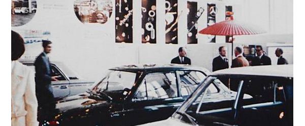 Farbfoto aus den 60er-Jahren: Personen und Fahrzeuge bei einem Empfang in einem Autohaus
