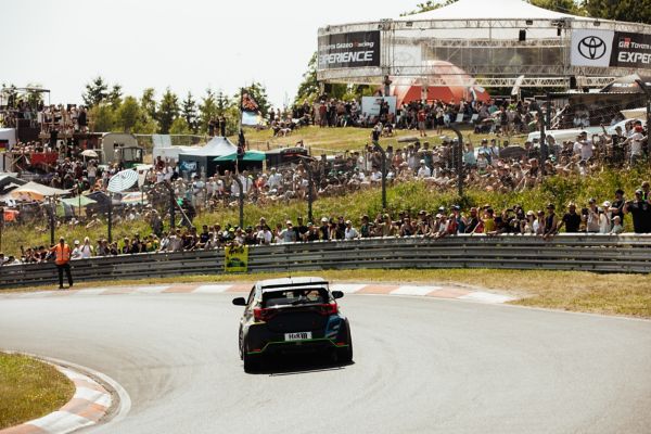 Schwarzer GR Yaris fährt auf dem Nürburgring durch eine Kurve. Im Hintergrund ist die Zuschauermenge zu sehen