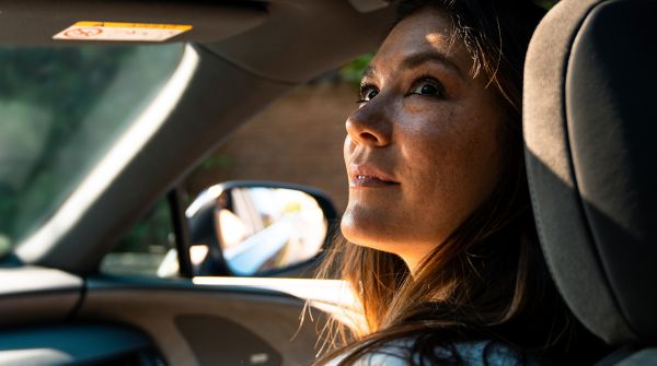 Eine Person blickt aus einem Lexus heraus und lächelt dabei
