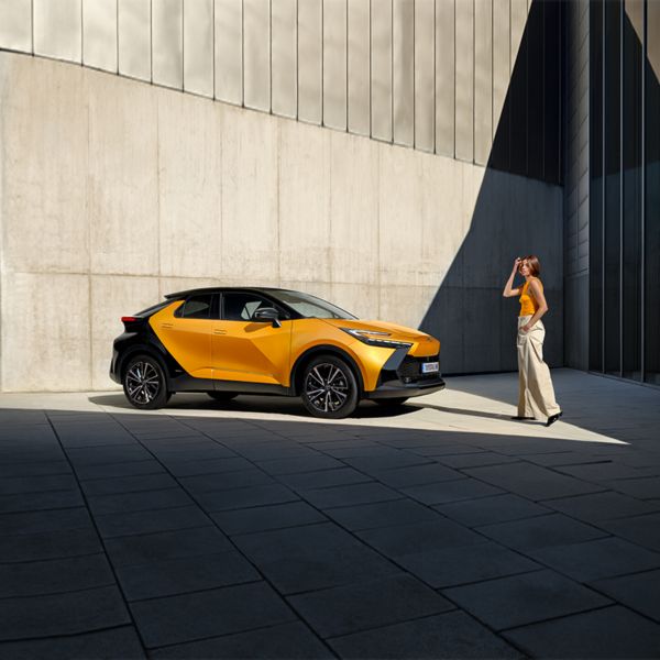 Малък градски СУВ Toyota C-HR с жена до него