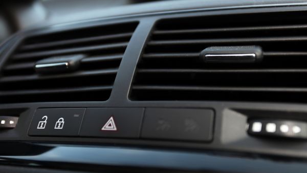 Die Nahaufnahme zeigt die zentralen Lüftungsgitter und Bedientasten eines Autos inklusive Warnblinkanlage und Türverriegelung.