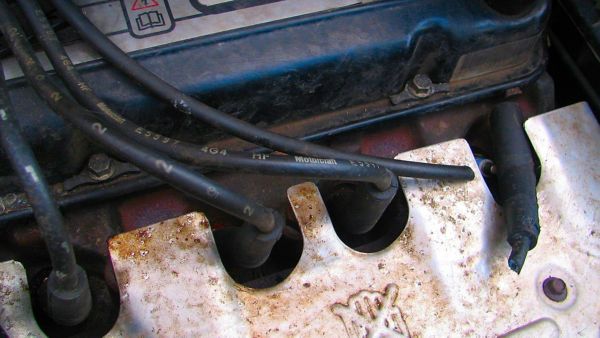 Nahaufnahme eines verschmutzten Motorraums mit beschädigten Zündkabeln als Hinweis auf Marderschäden