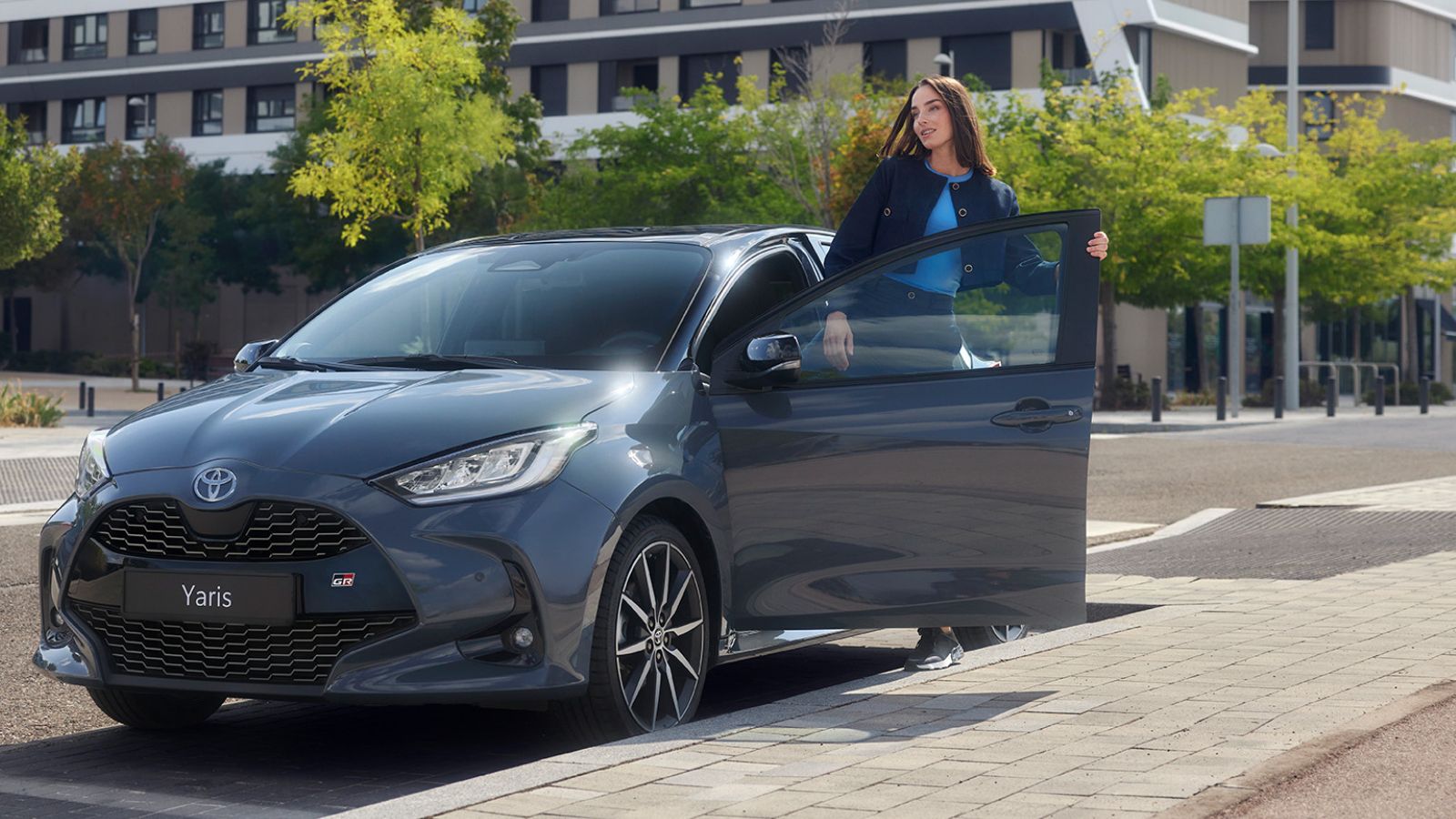 Kobieta wsiada do zaparkowanej przy ulicy Toyoty Yaris.