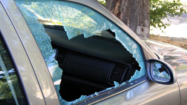 Die Nahaufnahme zeigt eine eingeschlagene Autoscheibe mit deutlich sichtbaren Glassplittern am Rahmen.