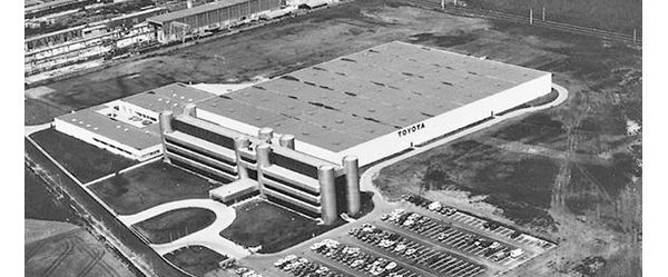 Schwarz-Weiß-Foto aus den 70er-Jahren: Luftaufnahme einer großen Autofabrik mit Toyota Schriftzug, daneben ein Parkplatz mit Autos