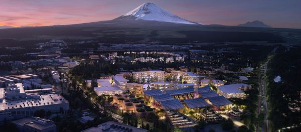 Eine moderne Siedlung aus der Vogelperspektive bei Dämmerung. Im Hintergrund ist der Mount Fuji zu sehen.