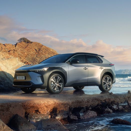 Stříbrné SUV na skalnatém pobřeží.