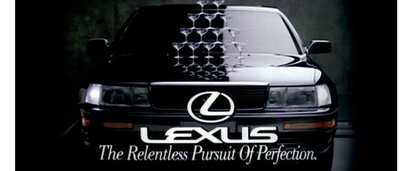 Werbeplakat eines Lexus von 1990, auf der Motorhaube eine Pyramide aus gefüllten Sektgläsern, Schriftzug „Lexus – The Relentless Pursuit Of Perfection“