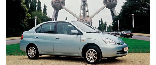 Ein blaugrauer Toyota Prius von 2000 vor dem Atomium in Brüssel, im Hintergrund parkende Autos