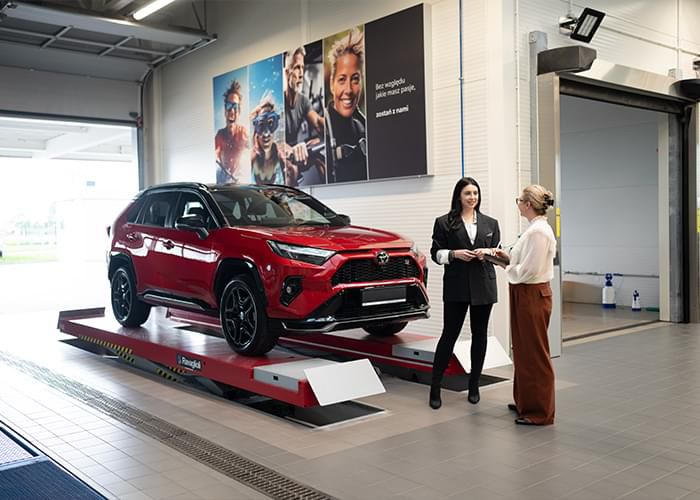 Klientka i konsultantka obok Toyoty na podnośniku