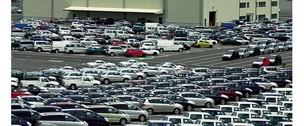 Erhöhte Aufnahme von einem Teil eines großen Parkplatzes, auf dem Dutzende fabrikneue Fahrzeuge zu sehen sind