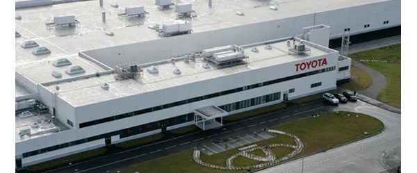 Luftaufnahme einer Autofabrik mit rotem Toyota Schriftzug, auf der Grünfläche davor ein Toyota Logo aus Steinen