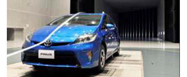 Blauer Toyota Prius in einem Windkanal, der durch weißen Nebel sichtbar gemachte Luftstrom fließt entlang der Motorhaube und Windschutzscheibe