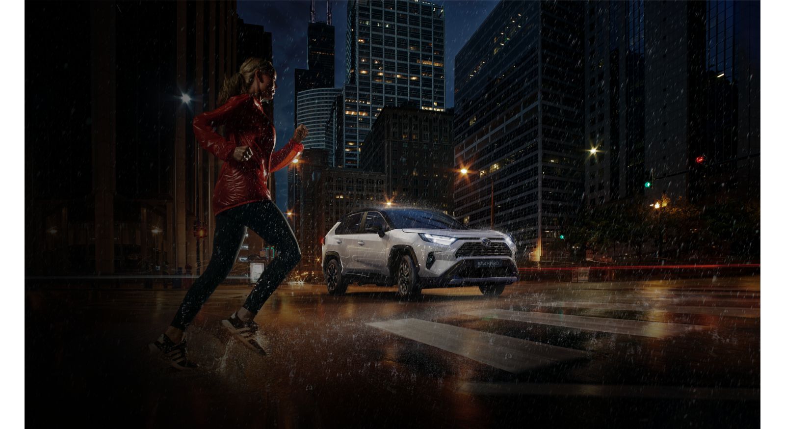 A Toyota RAV4 drives city streets in the dark and the rain  