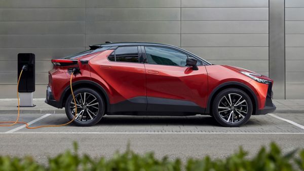 Ein Toyota RAV4 geparkt vor der Garage einer modernen Wohnung. Das Fahrzeug ist angeschlossen an eine Ladesäule