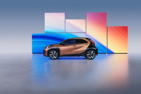 Aygo X zaparkowane przed kolorowymi ekranami LED