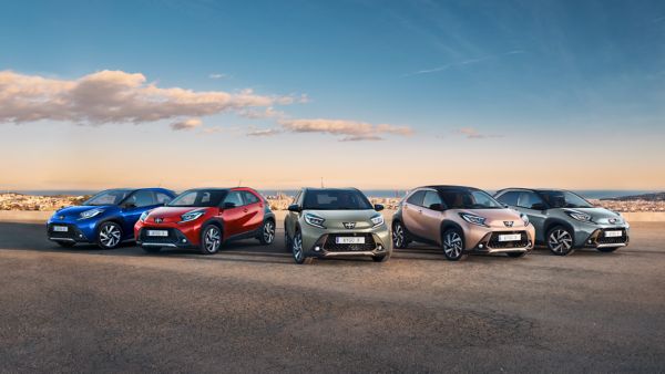 Five Aygo X vehicles parked in a field at sunset.