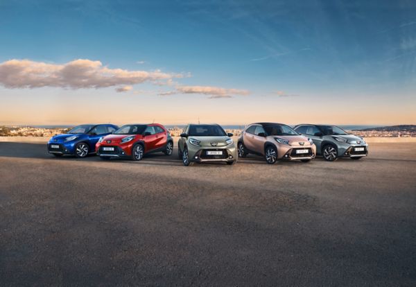 Reeks Toyota Aygo X-auto’s opgesteld op een panoramische weg bij zonsondergang, met verschillende carrosseriekleuren