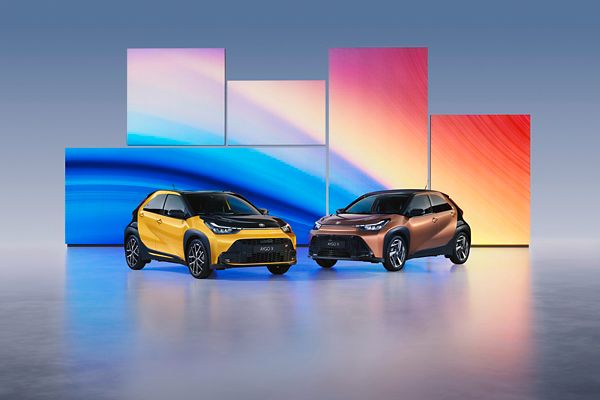 Aygo X ir Aygo X GR SPORT stovi priešais spalvingus šviesos diodų ekranus