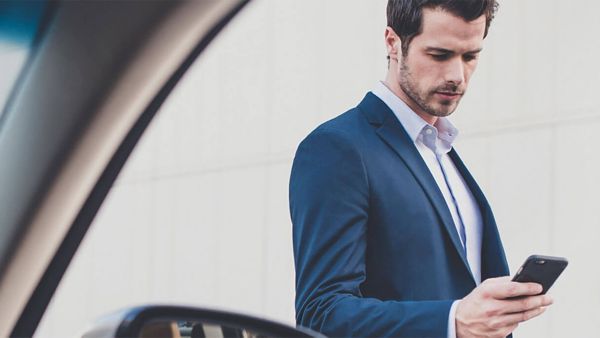 A man next to a Lexus checking his mobile phone