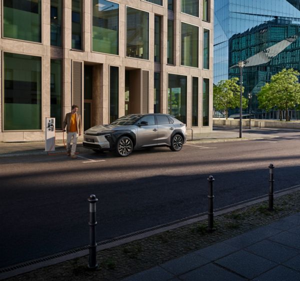 Ein Besitzer eines Toyota bZ4X lädt sein Fahrzeug an einer öffentlichen Ladestation auf der Straße auf.