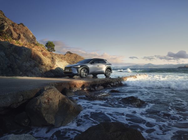 Toyota bZ4X parked on a rocky beach.