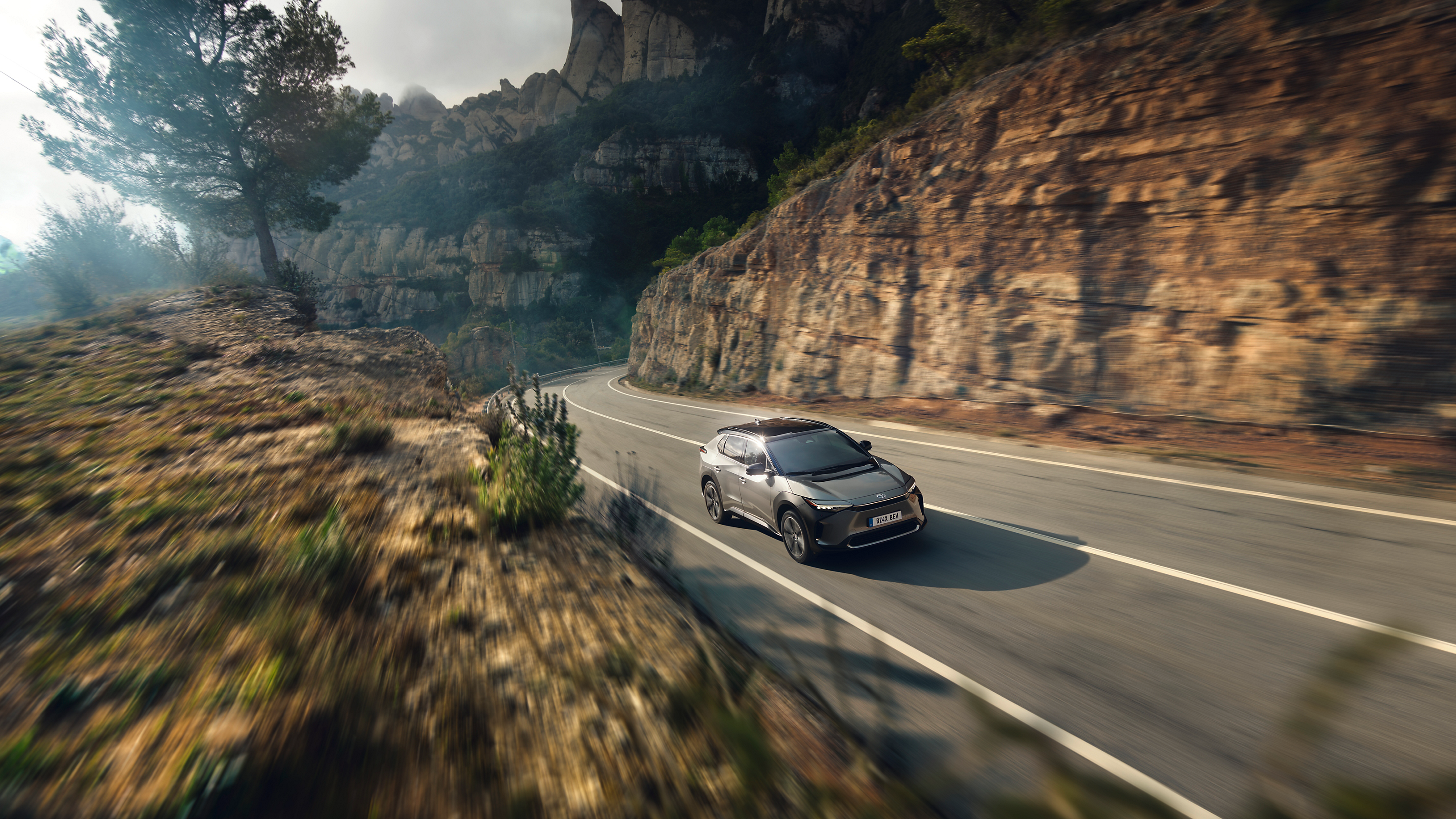 The all-terrain Toyota bZ4X against a composite backdrop of mountains and the city 