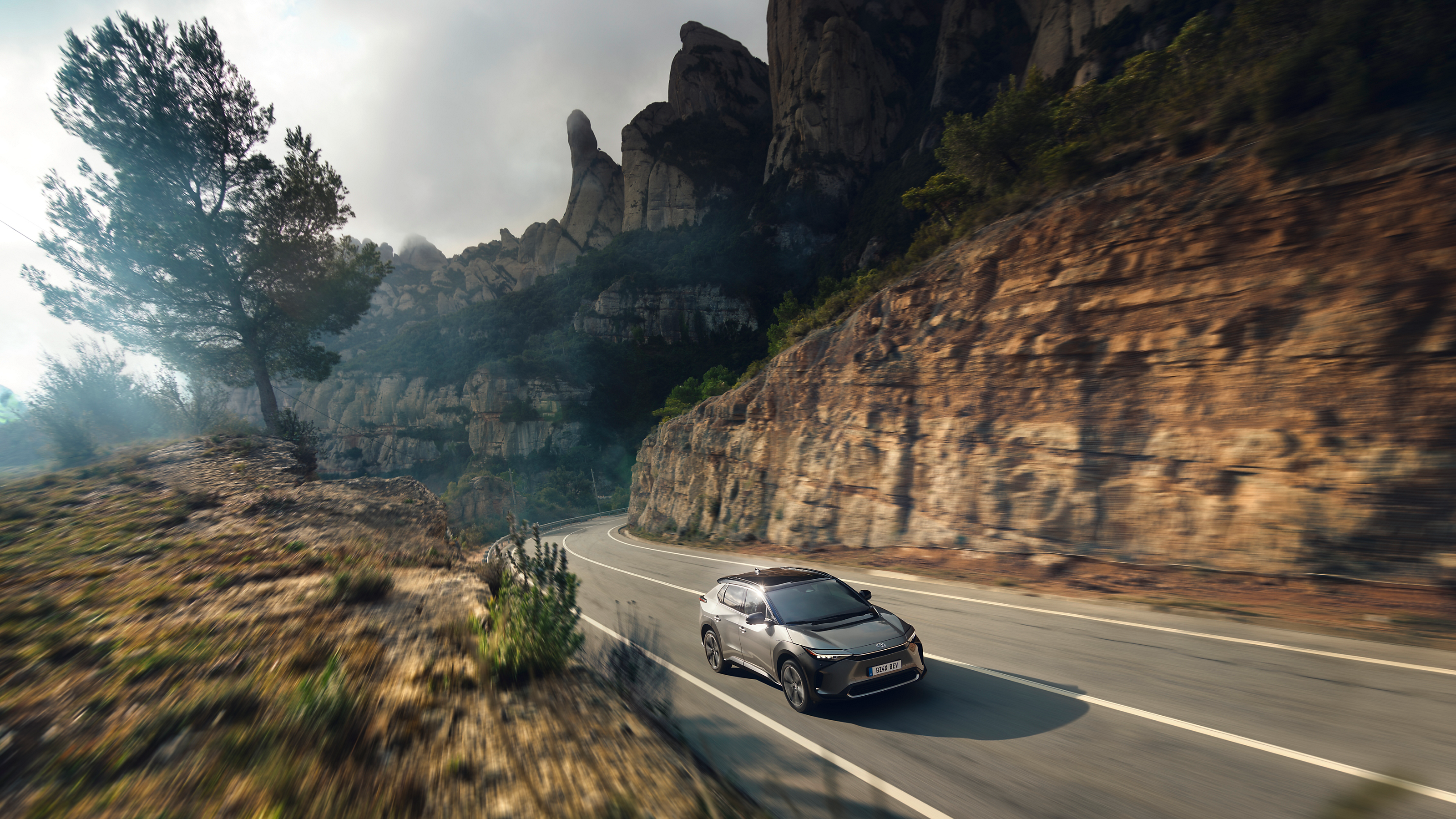 The all-terrain Toyota bZ4X against a composite backdrop of mountains and the city 
