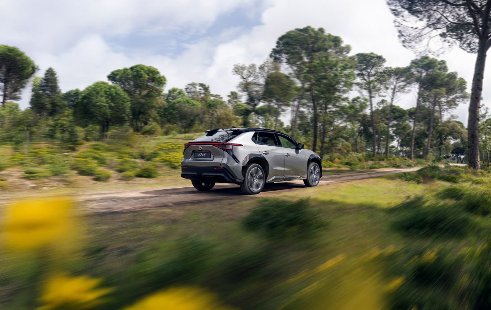 A Toyota bZ4X drives down a muddy track in the forest 