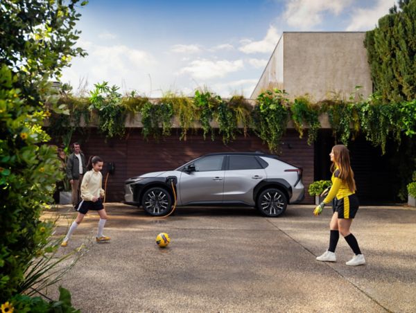 bZ4X op de oprit met spelende kinderen