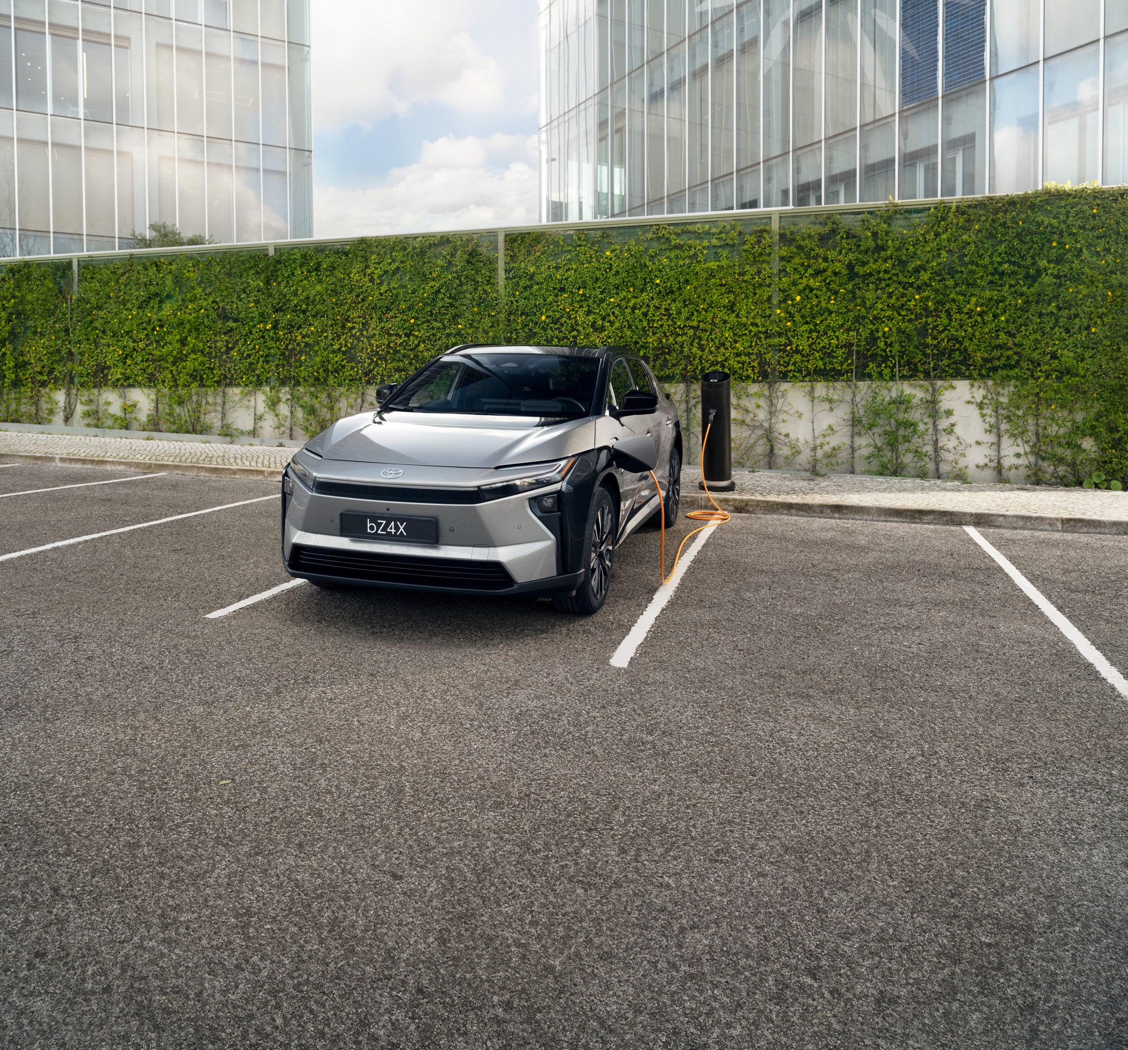 Megújult Toyota bZ4X szemből, modern épület előtt