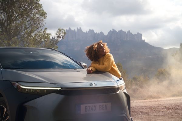 An owner and their Toyota bZ4X in a beautiful landscape