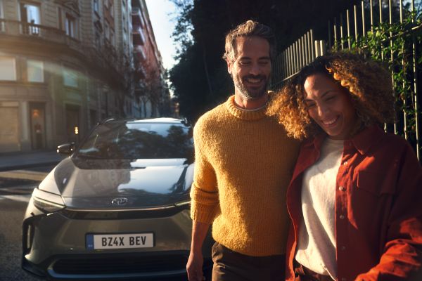 Smiling couple next to Toyota bZ4X