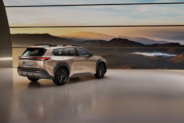 Image showing bz4X touring rear quarter in front of a giant led screen showing mountain range