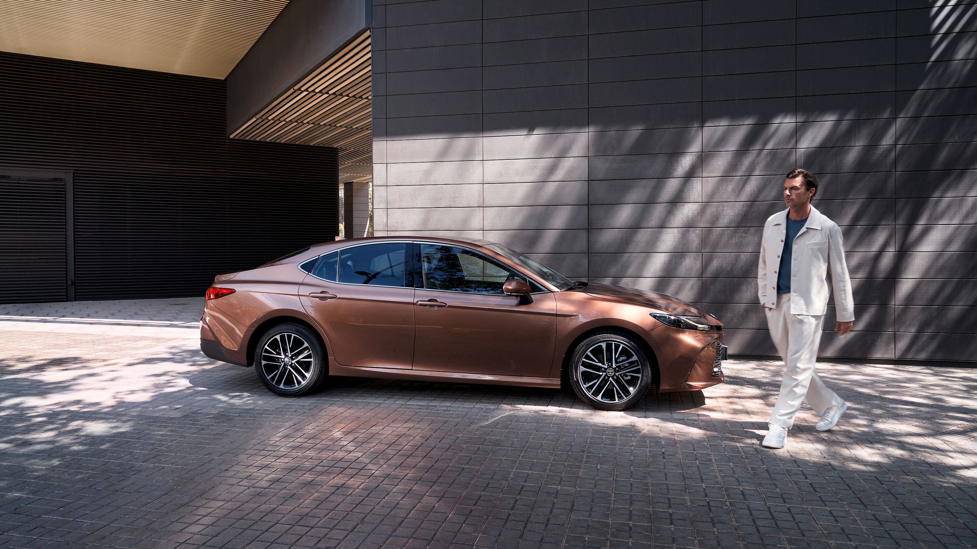 Toyota Camry, стоящая рядом с современным зданием.