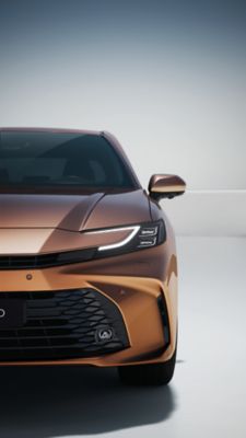 Seitlich-frontale Nahaufnahme der Windschutzscheibe eines silberner Toyota Corolla vor einem neutralen grauen Hintergrund.