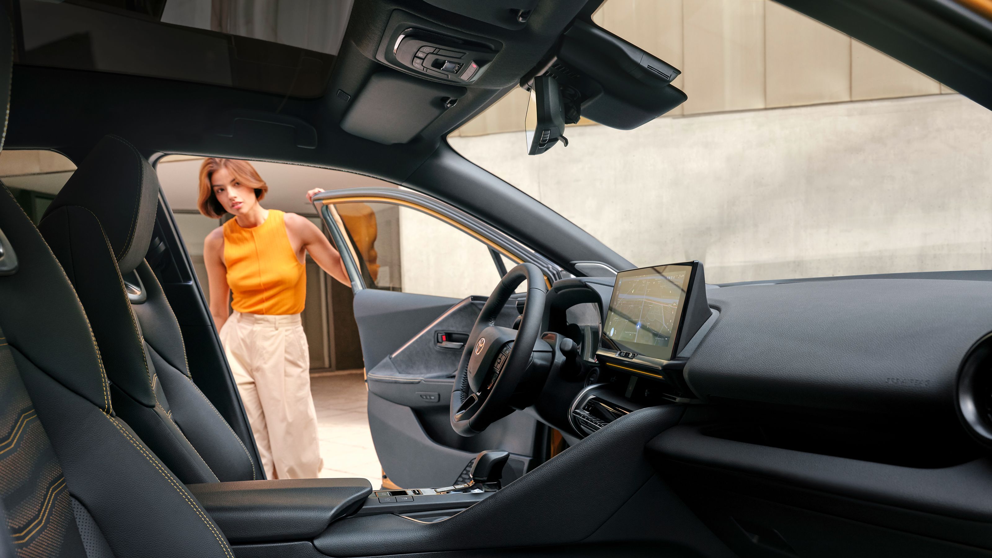 A Toyota C-HR customer opening the door of the car, exploring the roomy interior