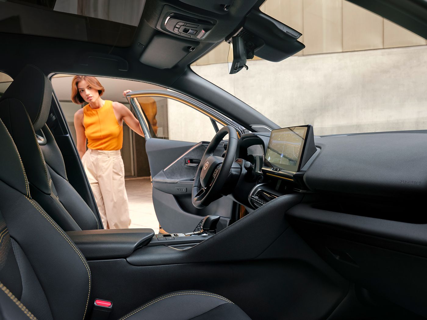 A Toyota C-HR customer opening the door of the car, exploring the roomy interior