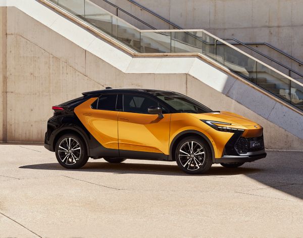 Seitenansicht eines gold schwarzen C-HR Hybrid mit beiger Wand und Treppen im Hintergrund.