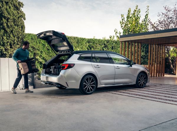 Man holding luggage next to Toyota Touring Sports parked